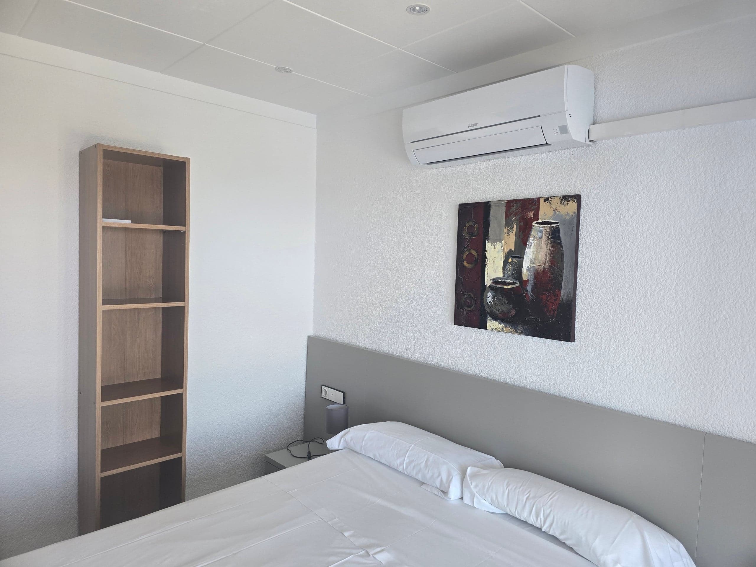 Bedroom with original painting, bookshelf and air conditioning