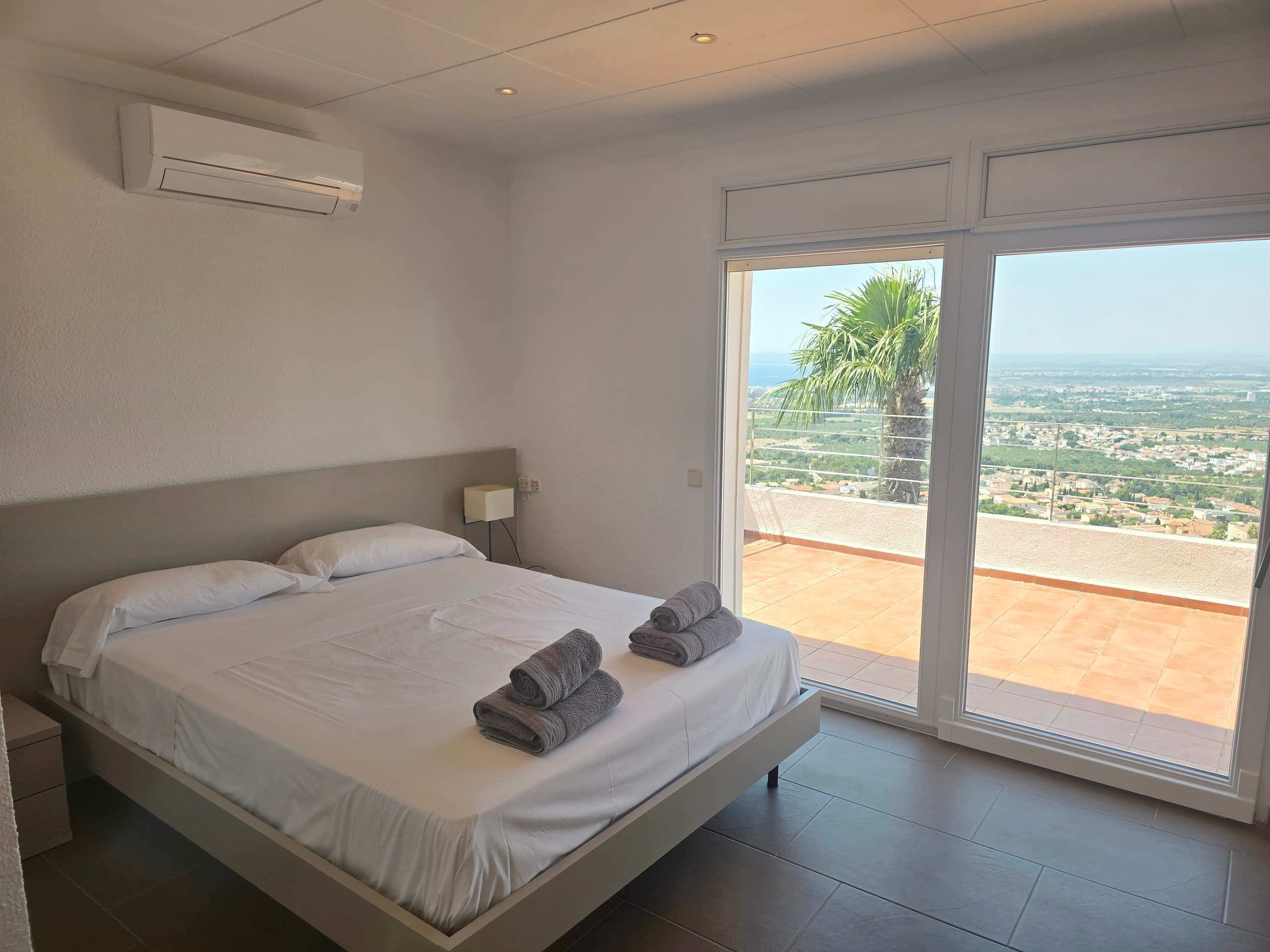 Bedroom with sliding door framing palm and bay view