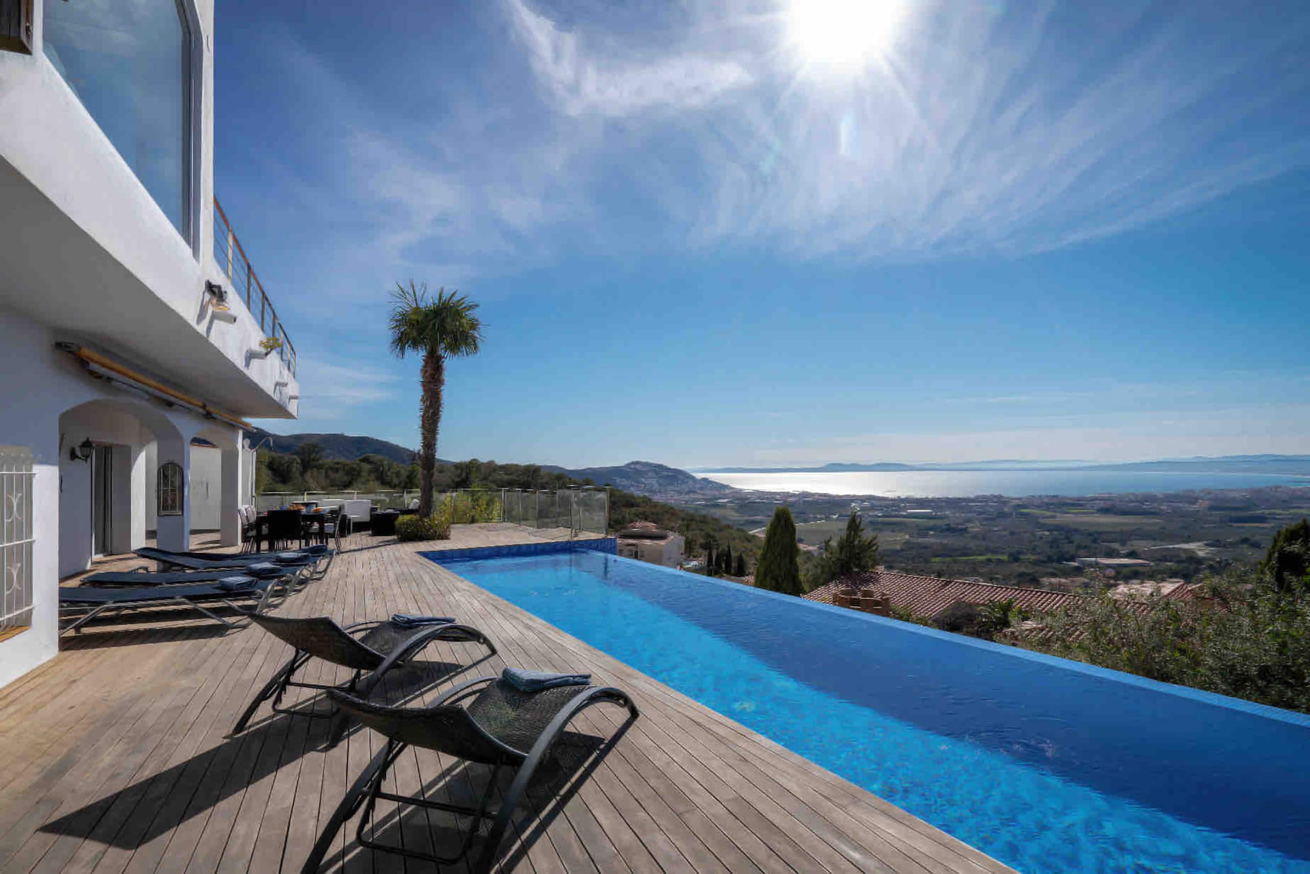 Pool deck and sun loungers with the Bay of Roses beyond